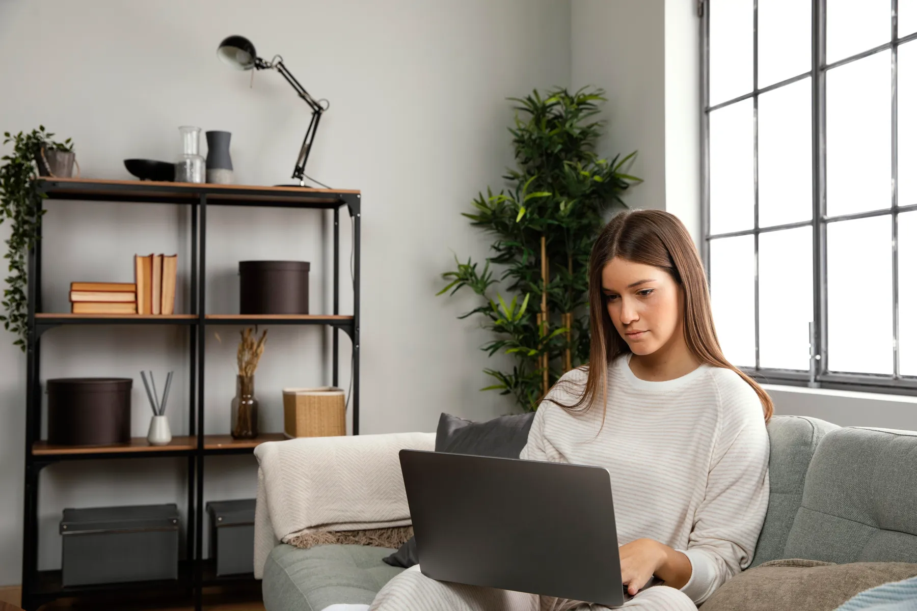 Mujer trabajando tranquila con su computador en la sala de su casa