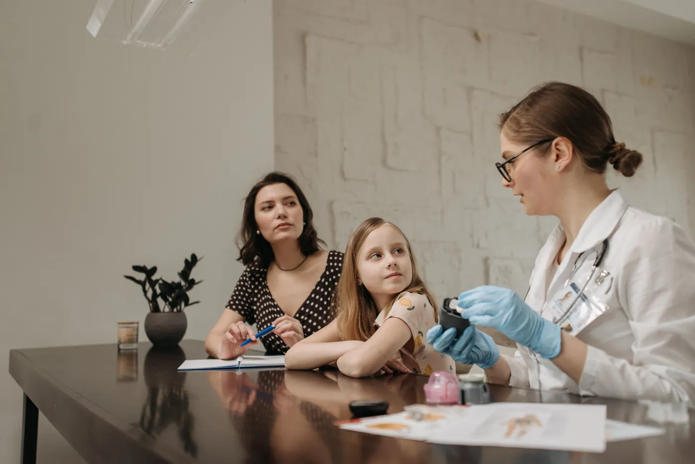 Pediatra atendiendo a una niña y a su mamá en el consultorio